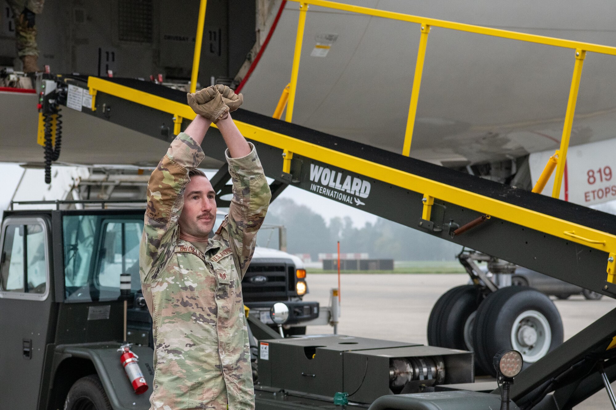 Airman guides a freight truck to a baggage conveyor