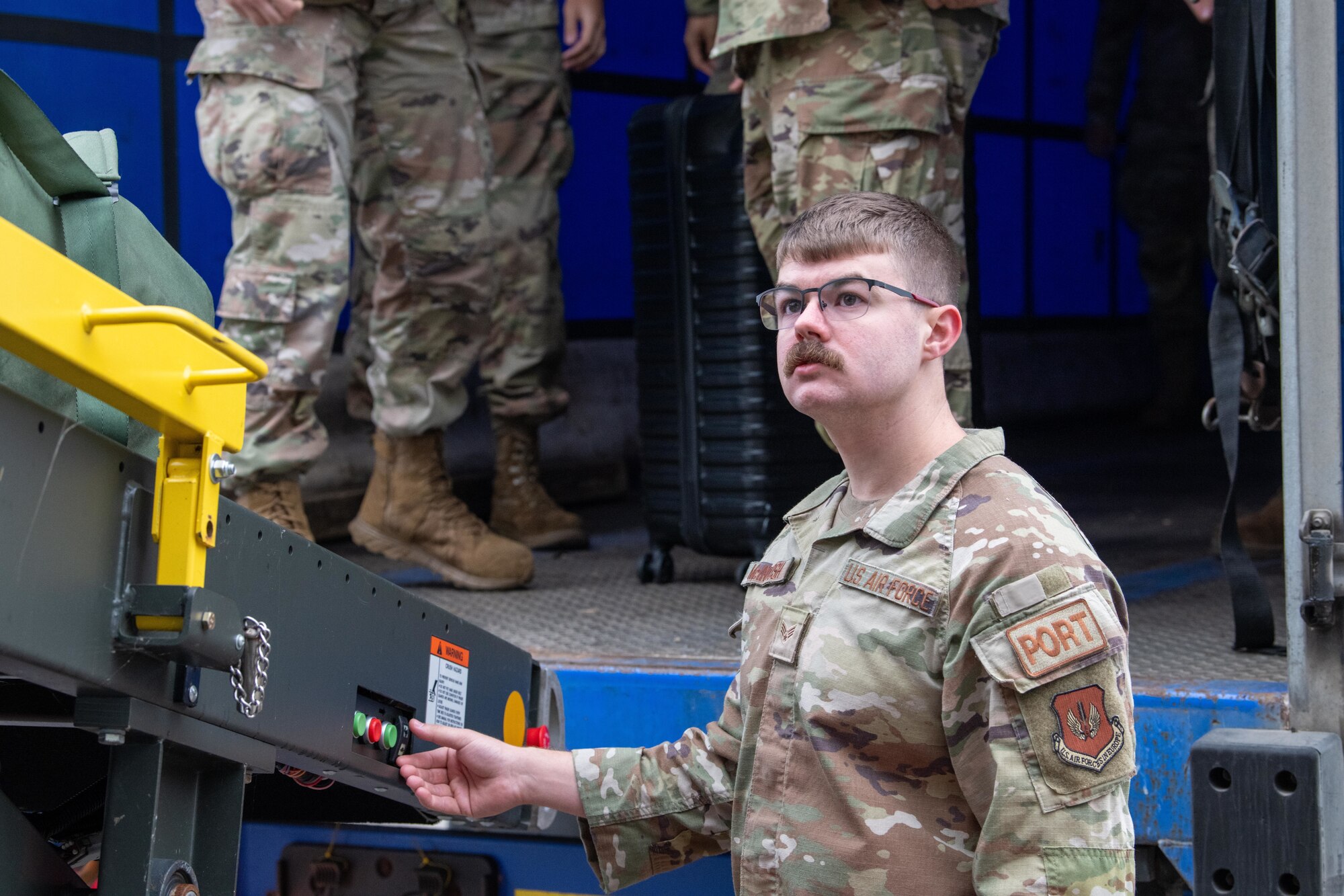 Airman operates a baggage conveyor during a baggage offload