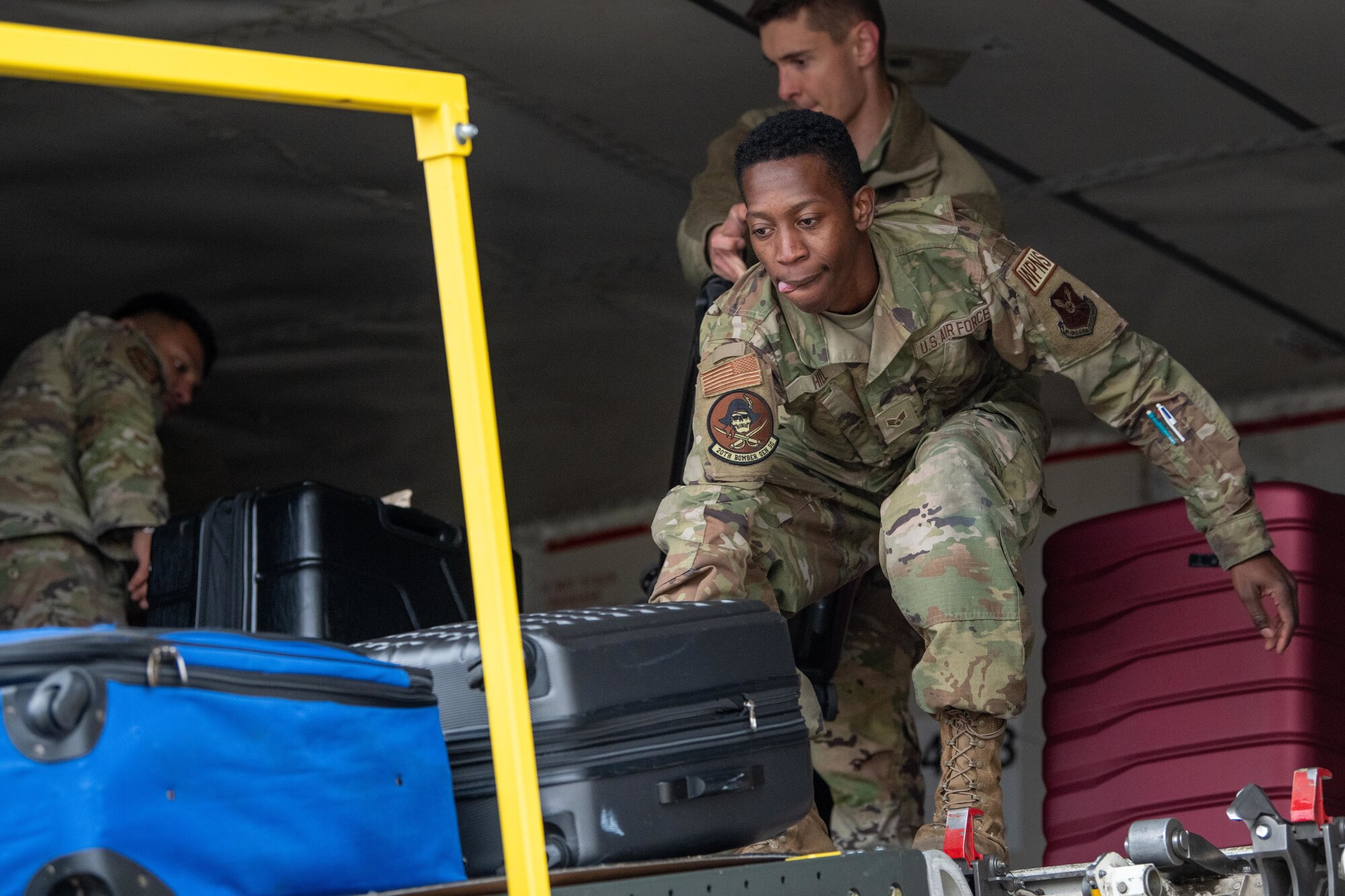 Airmen attached to the 20th Expeditionary Bomb Squadron offload luggage aboard an Omni Air International 777 aircraft