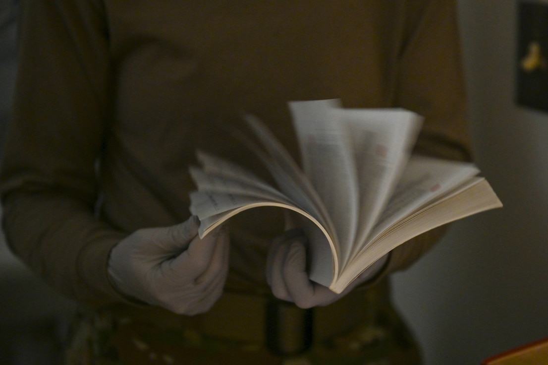 Close up photo of an Airman's hands flipping through a book.