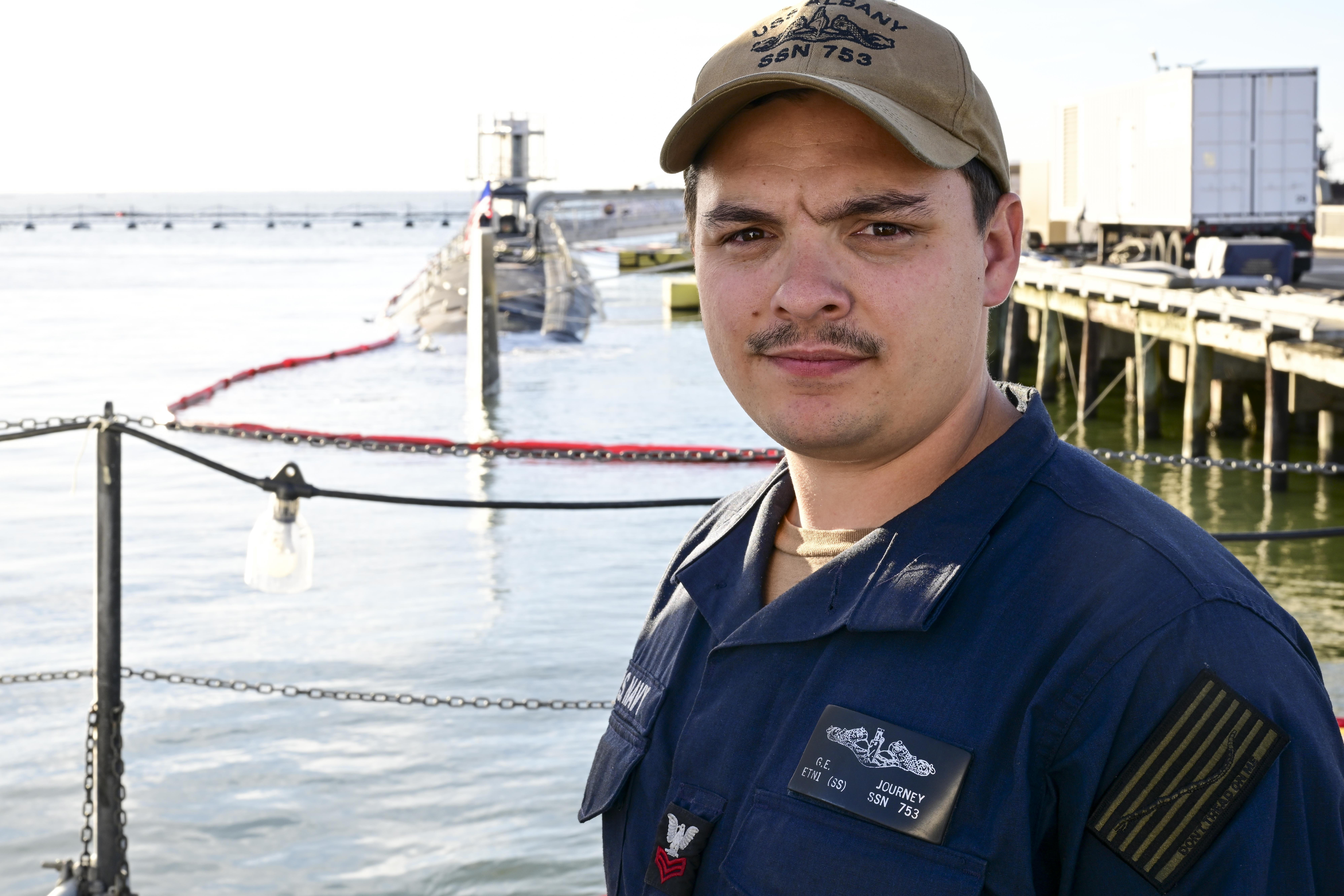 Sailor stands in front of a submarine