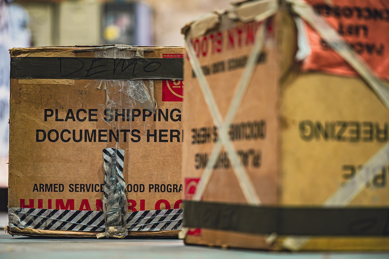 Two boxes containing donated human blood sits on the floor before an airdrop.