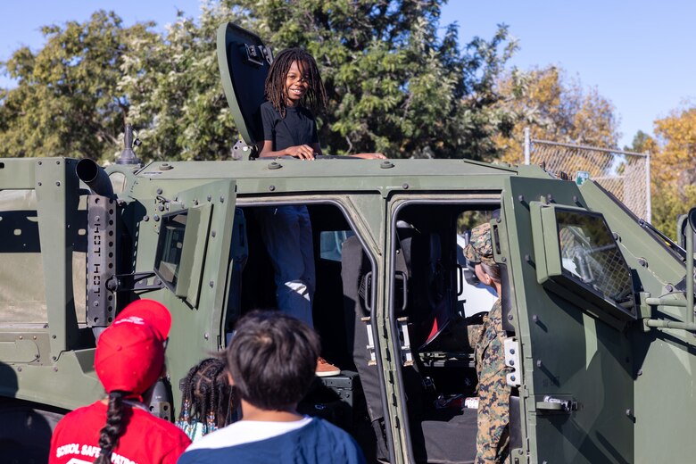 A student from Sunset Hills Elementary School stands inside a U.S. Marine Corps Joint Light Tactical Vehicle assigned to Marine Air Control Group 38, 3rd Marine Wing, during the school's annual Veterans Day program in San Diego, California, Nov. 7, 2024. The event featured active-duty Marines who presented equipment and engaged with students and parents about their military service. (U.S. Marine Corps photo by Sgt. Santicia Ambriez-Stippey)