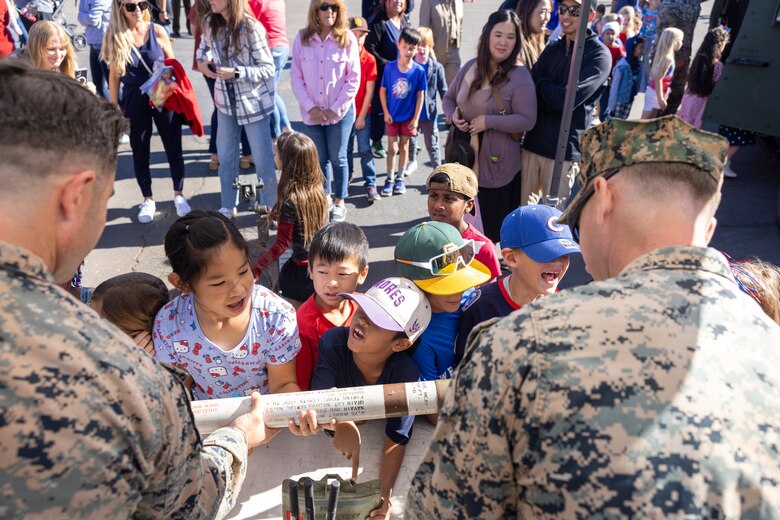 U.S. Marine Corps Staff Sgt. Luke G. Thomas, left, and Staff Sgt. Christiaan E. Jones, both explosive ordnance disposal technicians with Marine Wing Support Squadron (MWSS) 373, Marine Air Control Group 38, 3rd Marine Aircraft Wing, display various devices for students during the annual Veterans Day program at Sunset Hills Elementary School, San Diego, California, Nov. 7, 2024. The event featured active-duty Marines who presented equipment and engaged with students and parents about their military service. (U.S. Marine Corps photo by Sgt. Santicia Ambriez-Stippey)