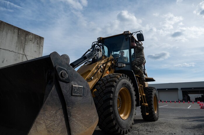 A U.S. Air Force Airman, assigned to the 35th Civil Engineer Squadron, demonstrates how to operate a Front-end Loader for a Snow Rodeo