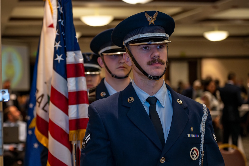 Airmen from the Honor Guard prepare to present the colors at an indoor ceremony