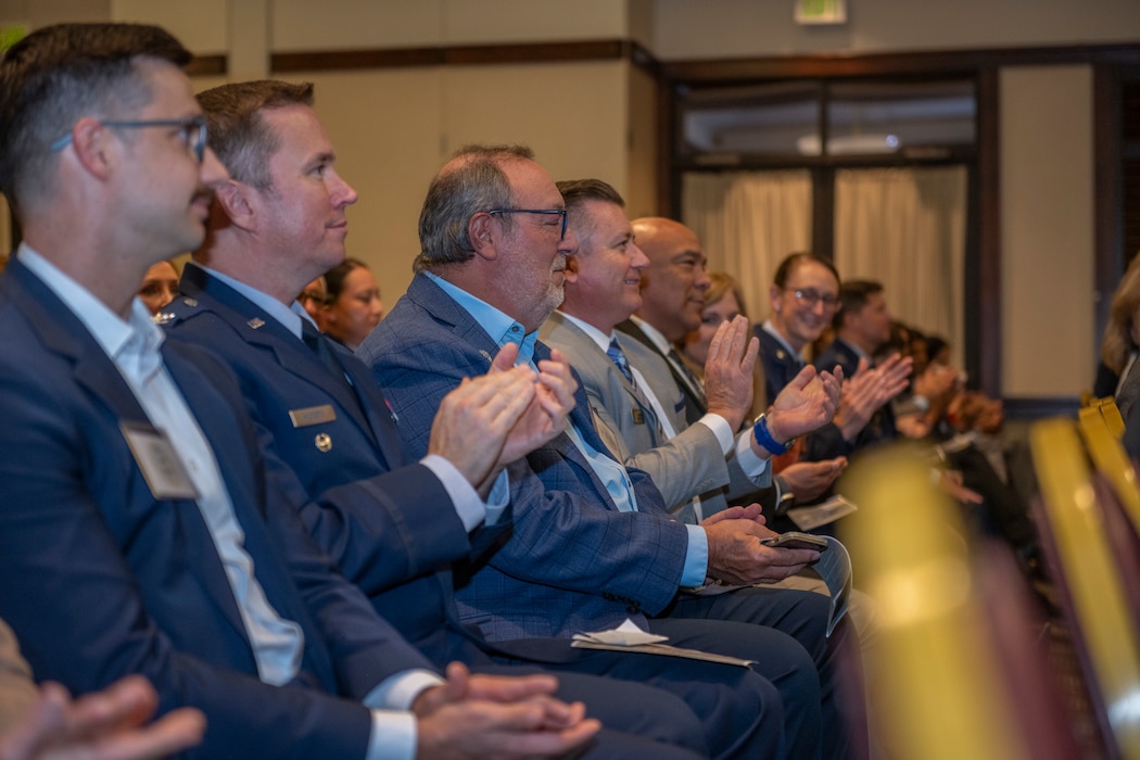 ceremony attendees sitting in chairs clap their hands