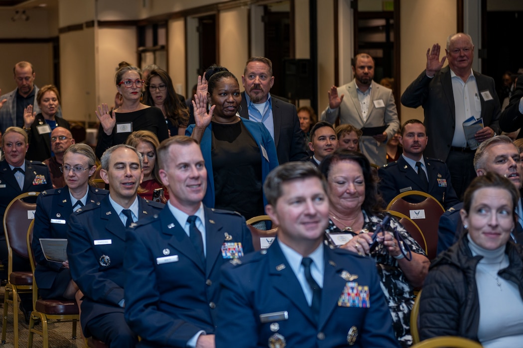 Honorary commanders raise their hands to take the honorary commander oath