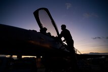 An Airman climbs on the side of an F-16