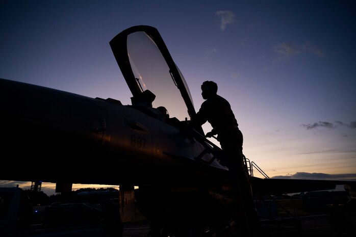 An Airman climbs on the side of an F-16