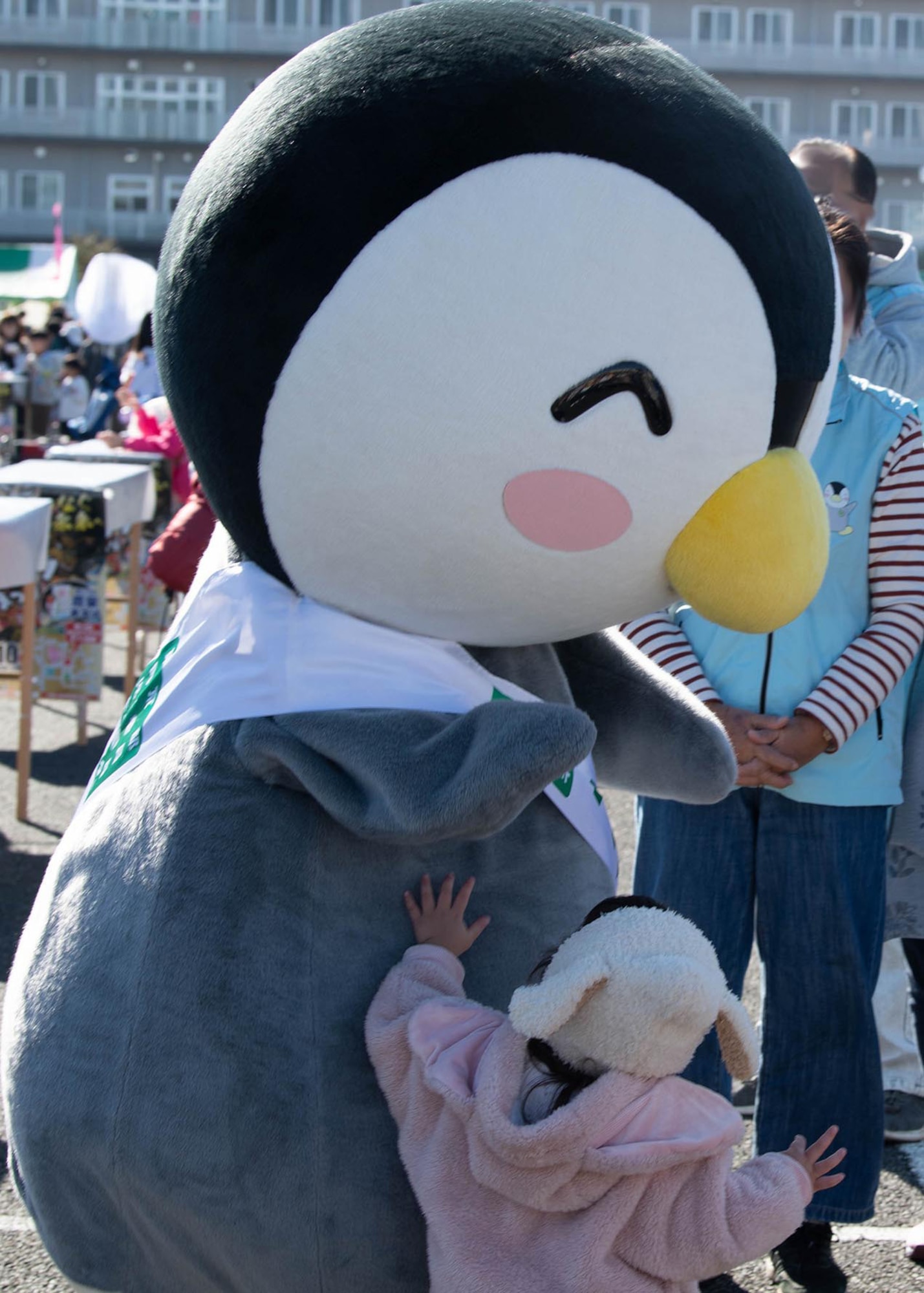 A child plays with a costumed penguin.