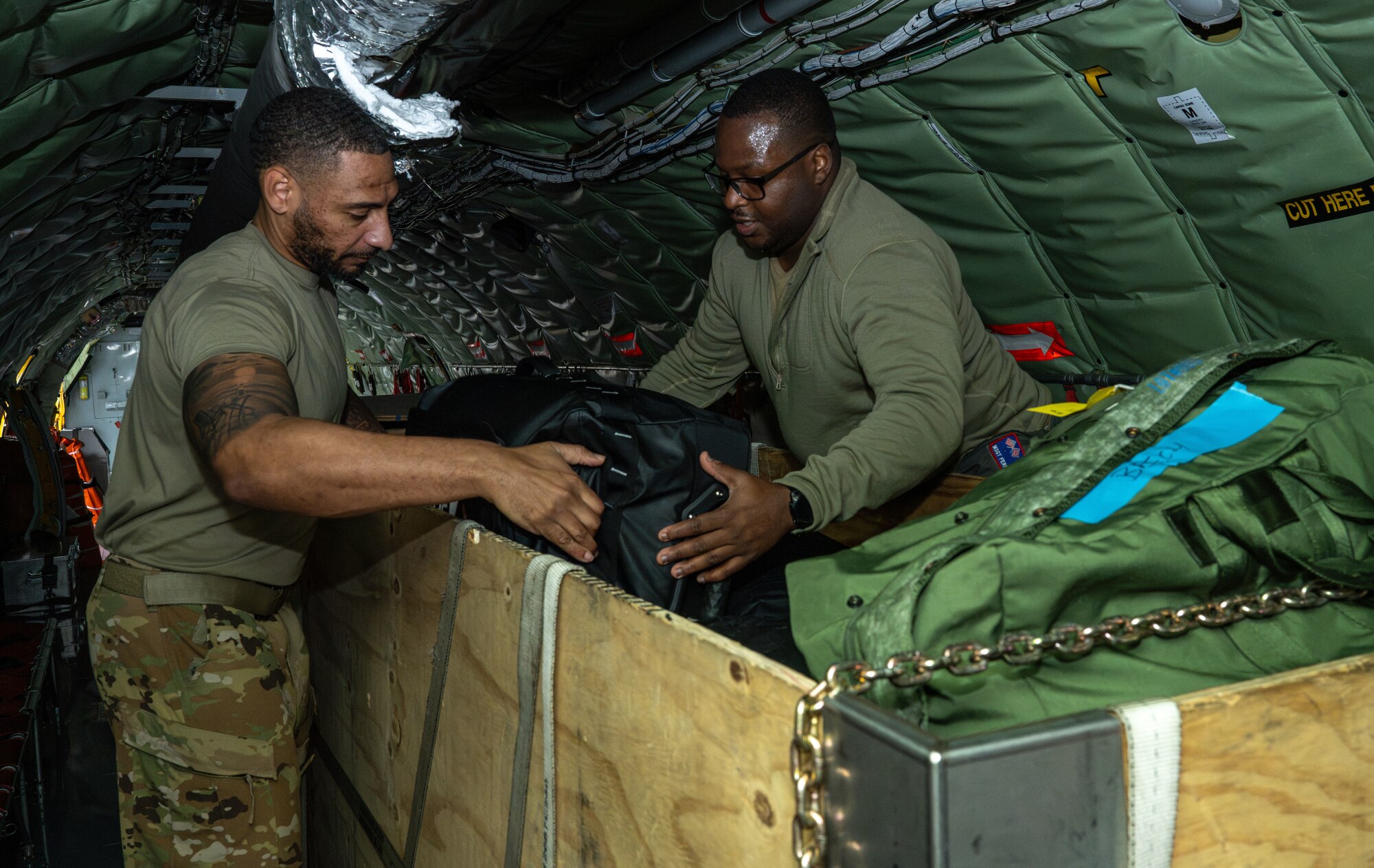 U.S. Air Force Tech. Sgt. Jamar Campbell, left, and Master Sgt. Fernando Brome, 351st Air Refueling Squadron boom operators, load cargo into wooden crates inside a KC-135 Stratotanker at Royal Air Force Mildenhall, England, Nov. 5, 2024.