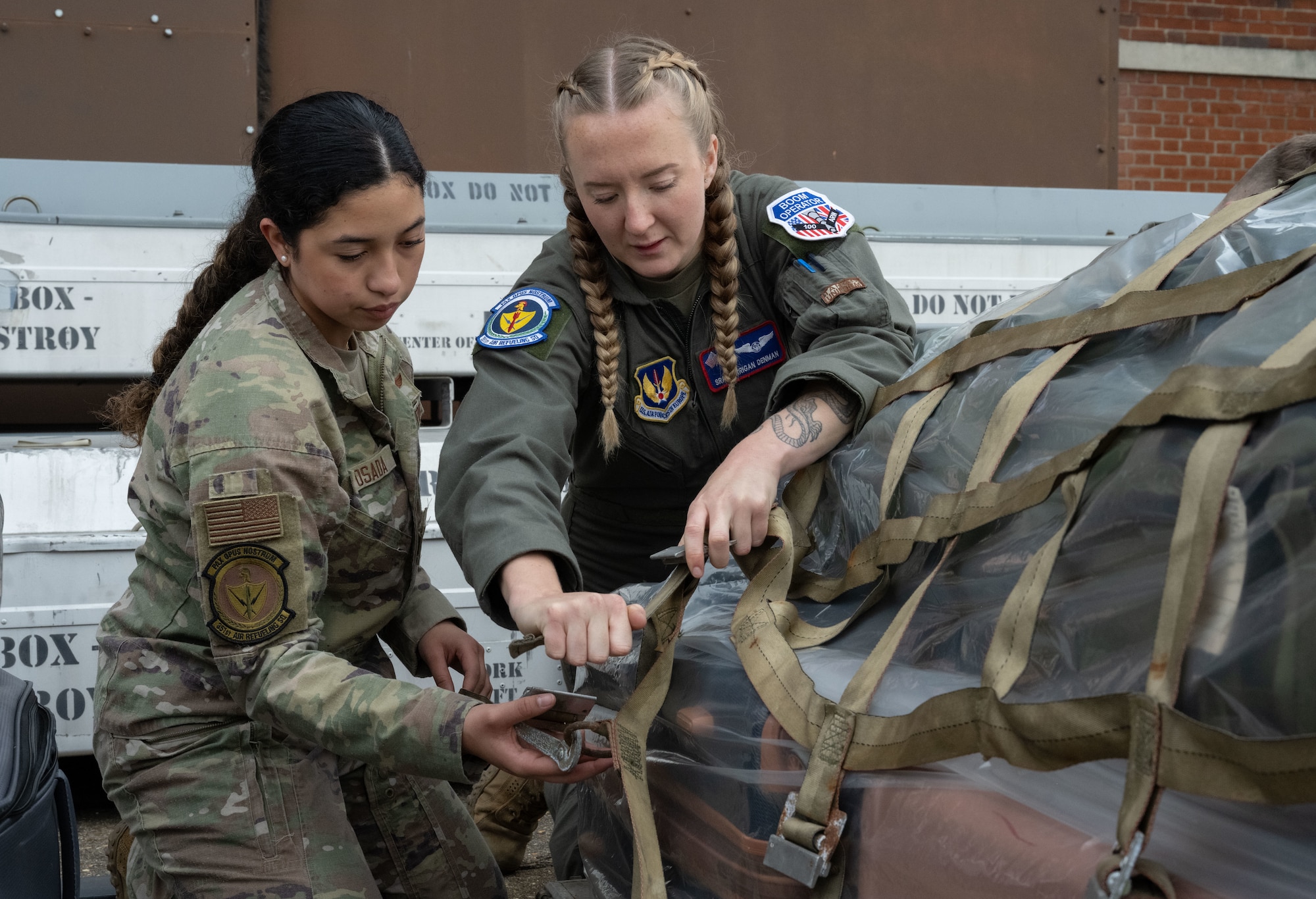 U.S. Air Force Airman Maya Posada, left, and Senior Airman Morrigan Denman, 351st Air Refueling Squadron boom operators, tighten straps on a cargo pallet at Royal Air Force Mildenhall, England, Nov. 5, 2024.
