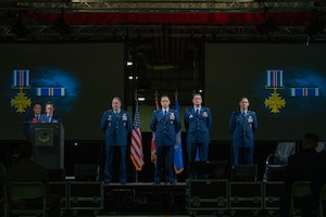 Distinguished Flying Cross recipients stand on stage to receive their decoration from USAFE commander