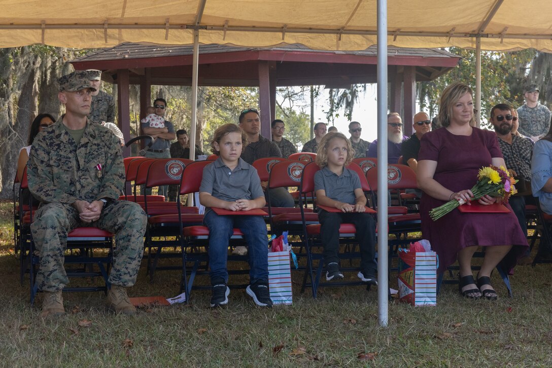 U.S. Marine Corps Master Sgt. Jeremiah Benjamin, left, a native of Nacogdoches, Texas and the signals intelligence and electronic warfare chief with Headquarters Battalion, 2d Marine Division, sits alongside his family during his retirement ceremony on Marine Corps Base Camp Lejeune, North Carolina, Nov. 8, 2024. The ceremony was held to honor Master Sgt. Benjamin’s 20 years of dedicated service. (U.S. Marine Corps photo by Lance Cpl. Alexander Canal Photo.)
