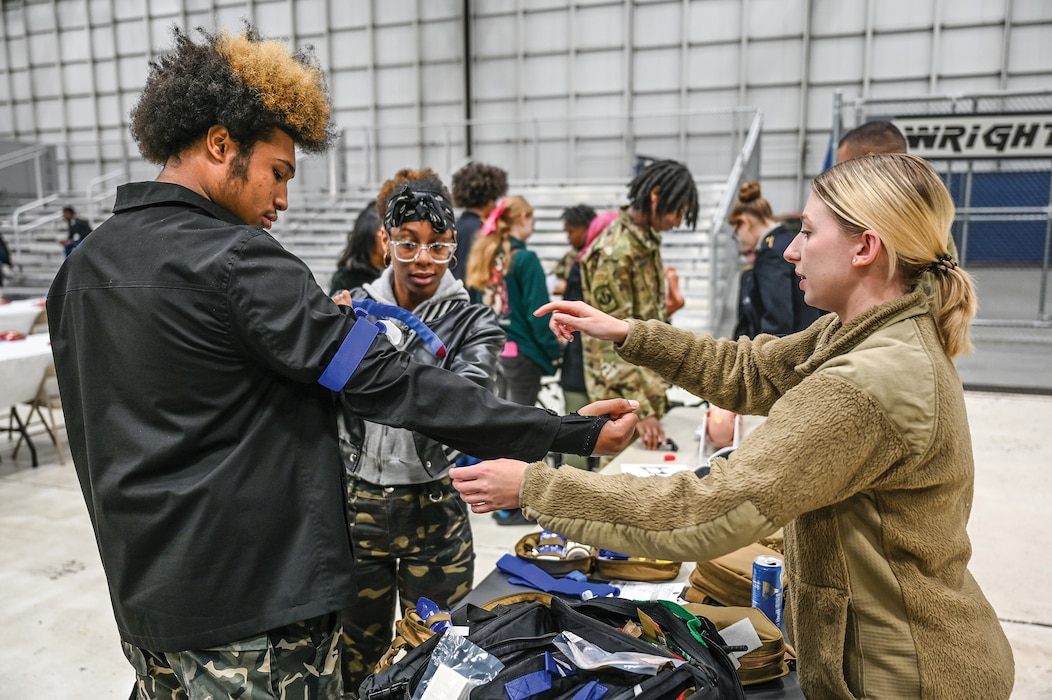 Staff Sgt. Hannah Elam, 445th Aeromedical Staging Squadron medical technician, demonstrates the use of a tourniquet to a Junior ROTC cadet from Dayton Public Schools during a visit with the 445th Airlift Wing at Wright-Patterson Air Force Base, Ohio, Oct. 18, 2024. During the visit cadets toured a C-17 Globemaster III aircraft and participated in demonstrations with the 445th ASTS, 445th Aerospace Medicine Squadron and 445th Security Forces Squadron.