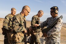 U.S. Marine Corps Sgt. Gerardo J. Bermudez, right, a combat marksmanship coach with Weapons and Field Training Battalion, Recruit Training Regiment, hands ammunition to recruits with Kilo Company, 3rd Recruit Training Battalion, during the table one course of fire at Marine Corps Base Camp Pendleton, California, Nov. 6, 2024. Table one covers the basic fundamentals of marksmanship and rifle safety in all shooting positions: sitting, kneeling, and the prone. (U.S. Marine Corps photo by Lance Cpl. Janell B. Alvarez)