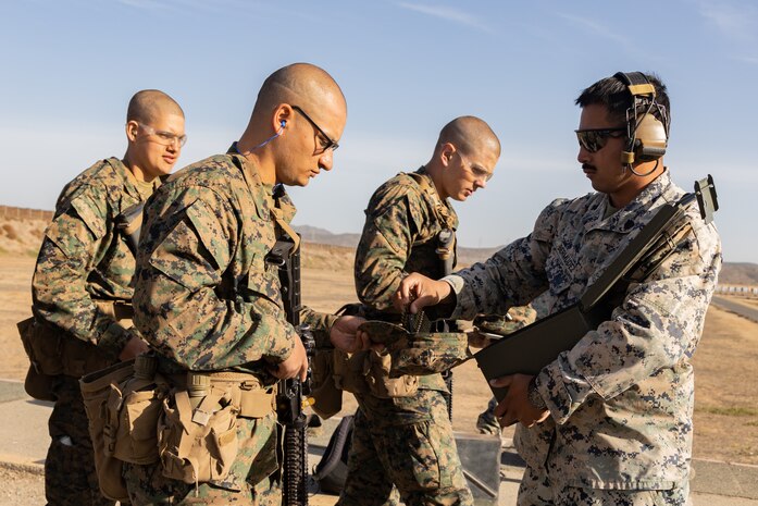 U.S. Marine Corps Sgt. Gerardo J. Bermudez, right, a combat marksmanship coach with Weapons and Field Training Battalion, Recruit Training Regiment, hands ammunition to recruits with Kilo Company, 3rd Recruit Training Battalion, during the table one course of fire at Marine Corps Base Camp Pendleton, California, Nov. 6, 2024. Table one covers the basic fundamentals of marksmanship and rifle safety in all shooting positions: sitting, kneeling, and the prone. (U.S. Marine Corps photo by Lance Cpl. Janell B. Alvarez)