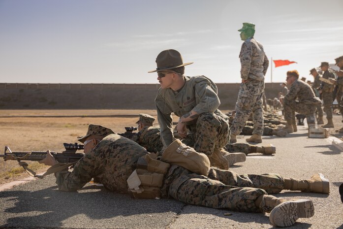 U.S. Marine Corps Sgt. Dmitruis Hemmingsen, a combat marksmanship coach with Weapons and Field Training Battalion, Recruit Training Regiment, assists a recruit with Kilo Company, 3rd Recruit Training Battalion, during the table one course of fire at Marine Corps Base Camp Pendleton, California, Nov. 6, 2024. Table one covers the basic fundamentals of marksmanship and rifle safety in all shooting positions: sitting, kneeling, and the prone. (U.S. Marine Corps photo by Lance Cpl. Janell B. Alvarez)