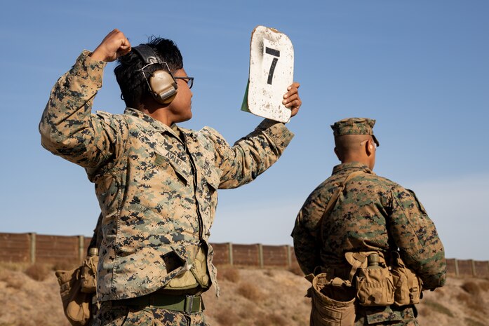 U.S. Marine Corps Lance Cpl. Joaqui Atalig, a combat marksmanship coach with Weapons and Field Training Battalion, Recruit Training Regiment, alerts to speed up target seven during the table one course of fire with Kilo Company, 3rd Recruit Training Battalion at Marine Corps Base Camp Pendleton, California, Nov. 6, 2024. Table one covers the basic fundamentals of marksmanship and rifle safety in all shooting positions: sitting, kneeling, and the prone. (U.S. Marine Corps photo by Lance Cpl. Janell B. Alvarez)