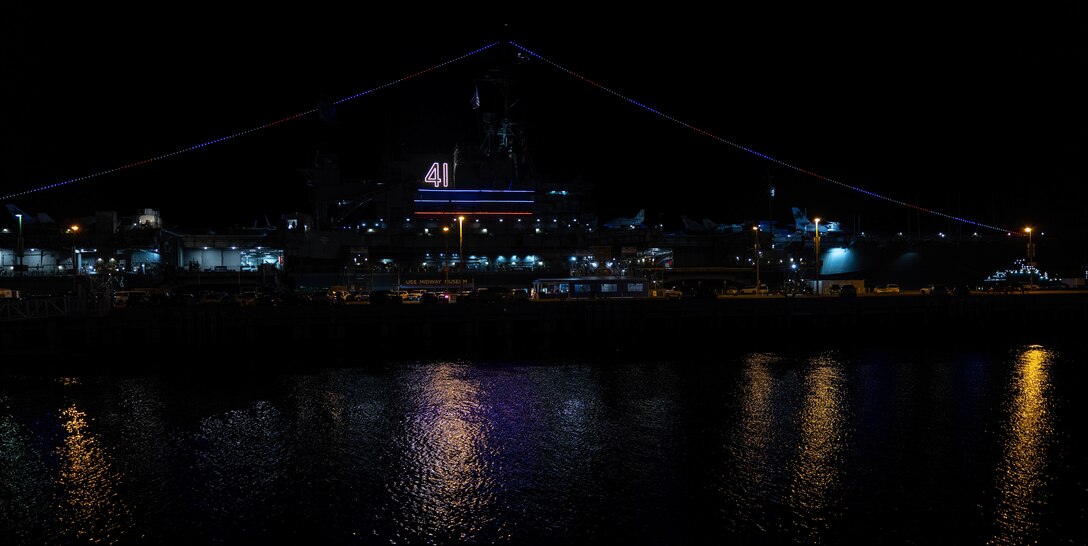 The USS Midway Museum illuminates during the kick-off of Fleet Week San Diego, Nov. 7, 2024. FWSD is an opportunity for San Diego residents and tourists to meet their Navy, Marine Corps and Coast Guard teams and experience America’s sea services. During fleet week, service members participate in various community relations events, showcase capabilities and equipment to the community, and enjoy the hospitality of San Diego and the surrounding area. (U.S. Marine Corps photo by Sgt. Brian A. Stippey)