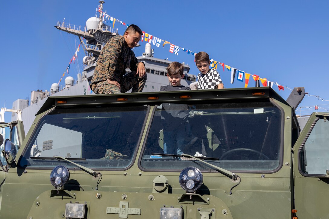 A U.S. Marine Corps logistics vehicle system operator with I Marine Expeditionary Force gives children a tour of a U.S. Marine Corps Logistics Vehicle System Replacement assigned to I MEF during Fleet Week San Diego at Broadway Pier, San Diego, Nov. 9, 2024. FWSD is an opportunity for San Diego residents and tourists to meet their Navy, Marine Corps and Coast Guard teams and experience America’s sea services. During fleet week, service members participate in various community relations events, showcase capabilities and equipment to the community, and enjoy the hospitality of San Diego and the surrounding area. (U.S. Marine Corps photo by Sgt. Gabriel Tavarez)