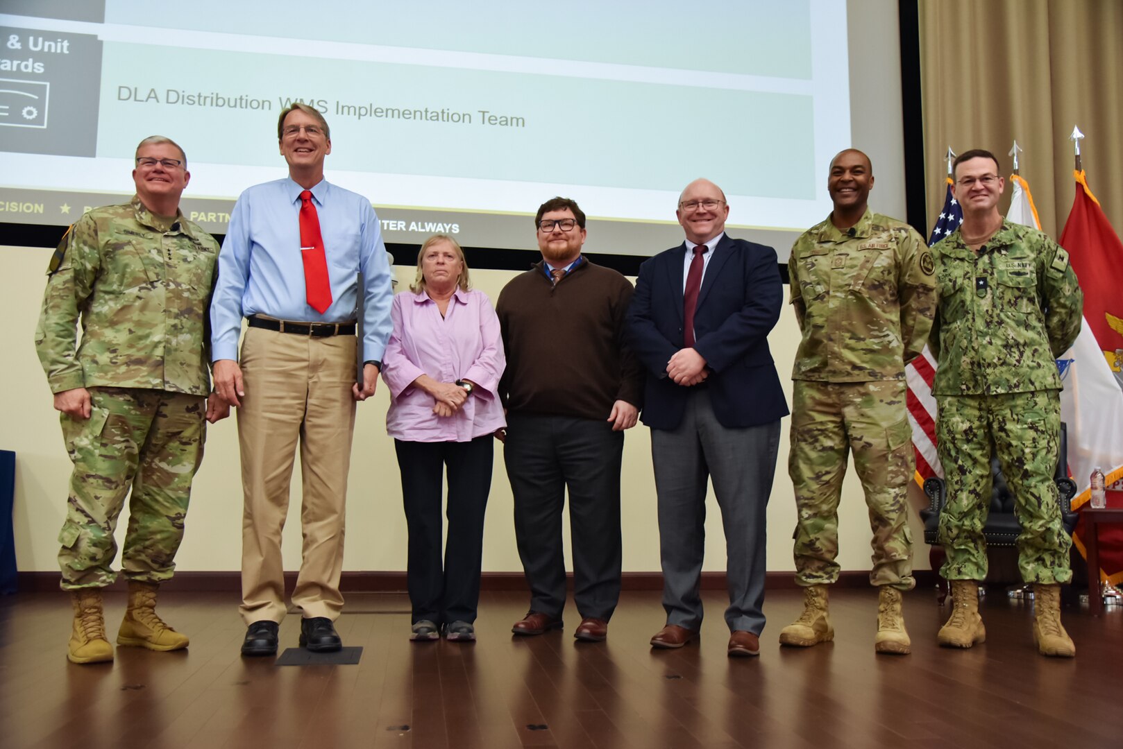A group of people stand in a single line on a stage.