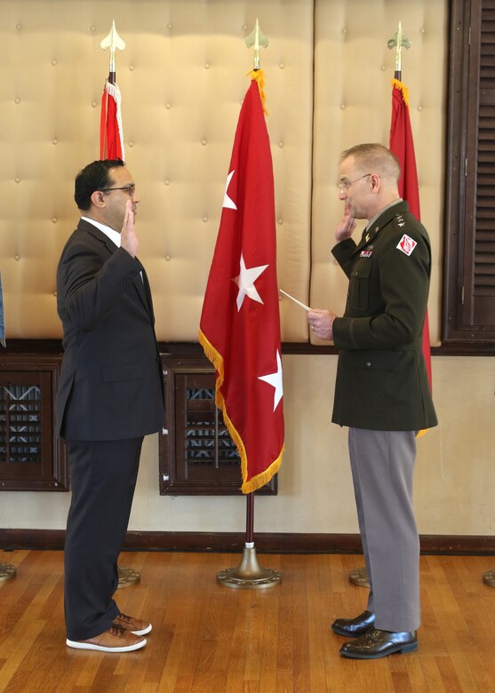 A man in a senior U.S. Army uniform administers an oath to a man wearing a suit.