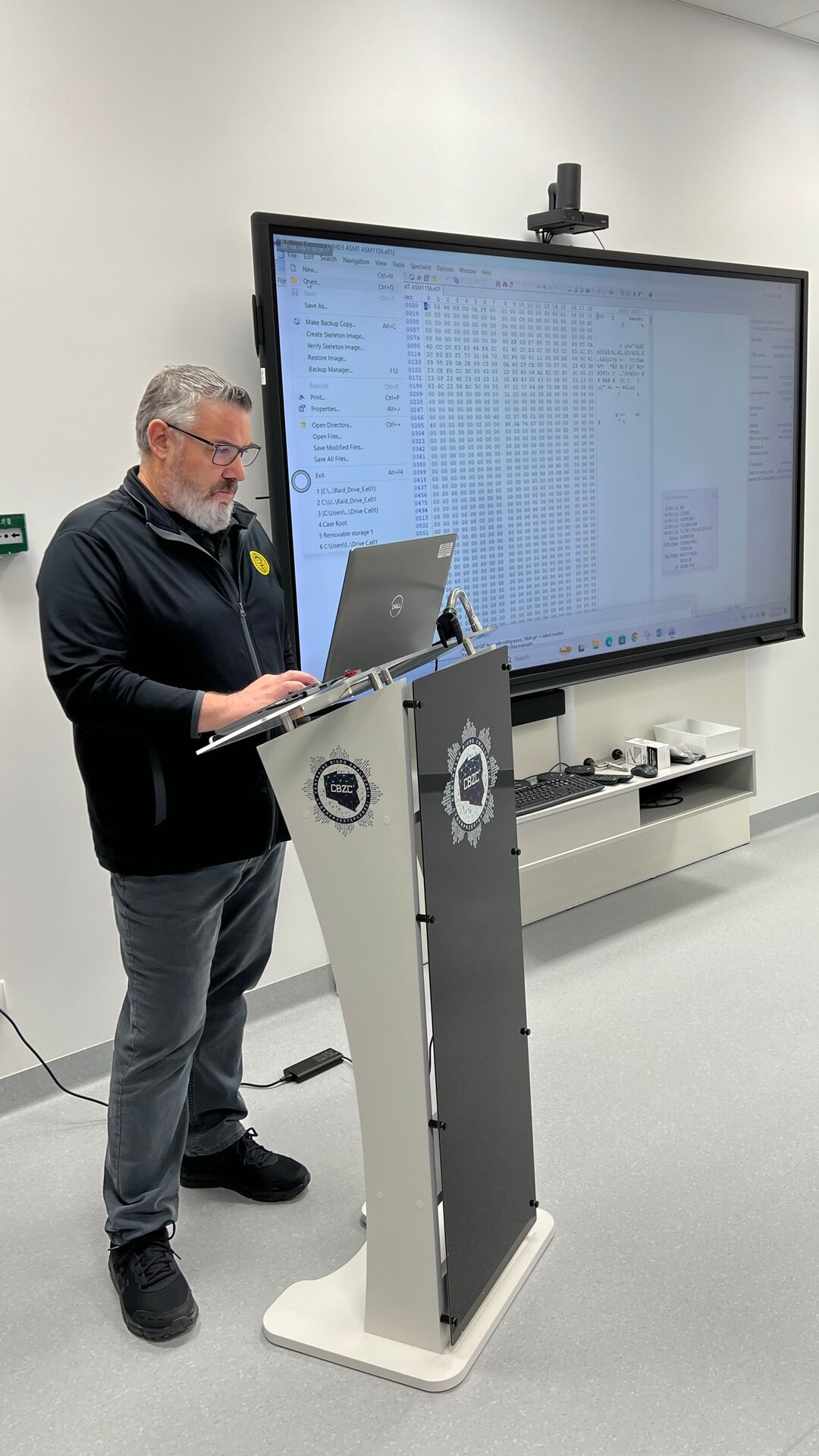 An Army CID special agent stands at a lectern while instructing in a classroom in Poland