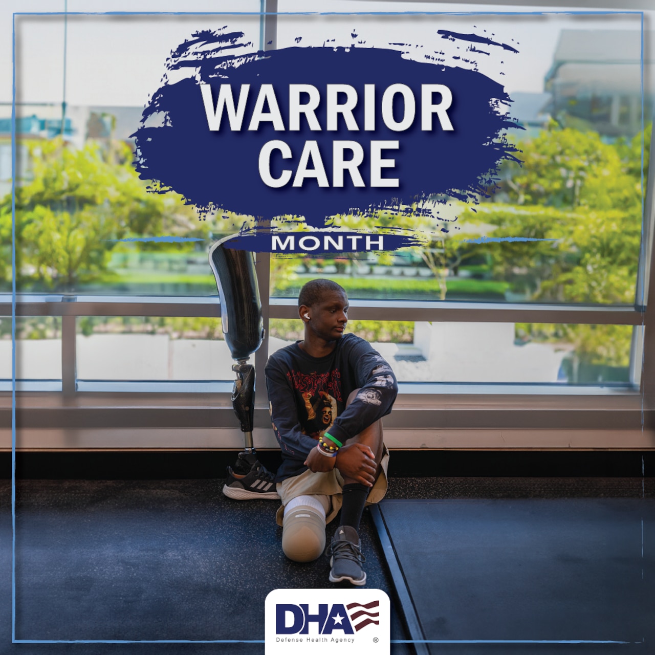 An amputee sits on the floor in a building by a window with the words “Warrior Care Month” overhead.