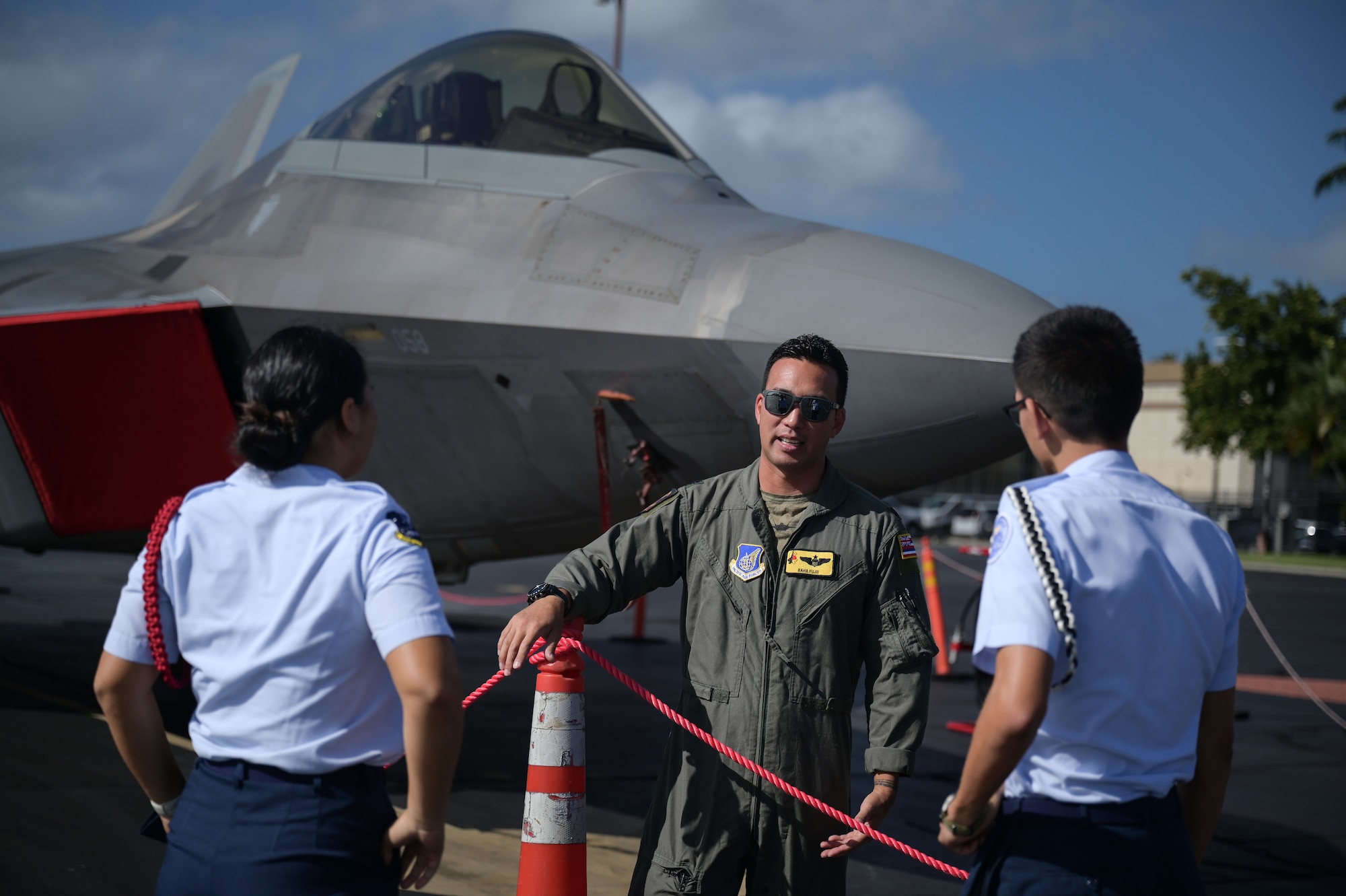 Airman speaks to students in front of an aircraft.