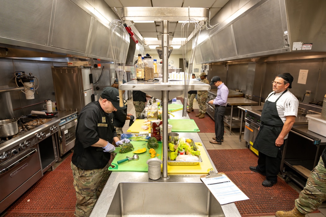 Airmen cook in kitchen.