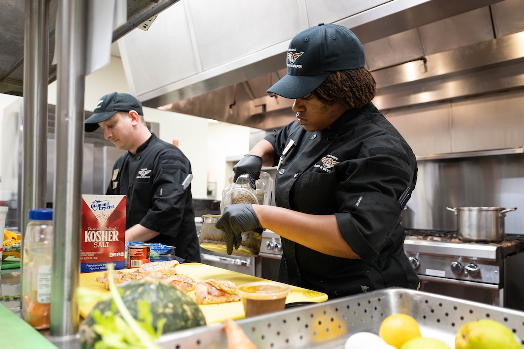 Airman adds seasoning to chicken.