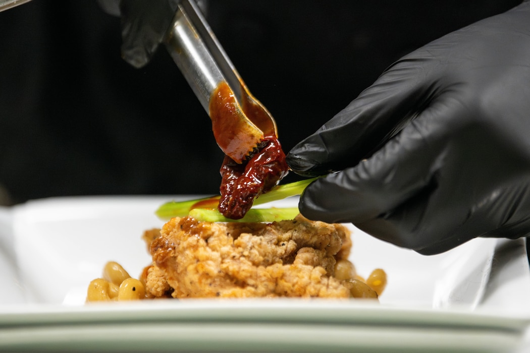 Airman puts food onto plate.