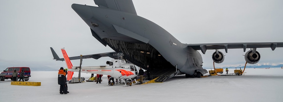 U.S. Air Force Airmen, all loadmasters from Team McChord, lower a ramp down between the Antarctic ice and the ramp of a C-17 Globemaster III, at Phoenix Airfield, Antarctica, Oct. 20, 2024.