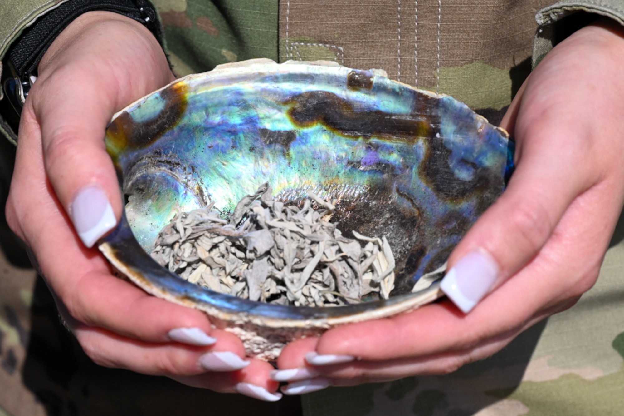 U.S. Air Force Staff Sgt. Casarah Pine, a flight instructor for the USAF Honor Guard at Joint Base Anacostia-Bolling, holds an abalone bowl with sage to burn for an energy cleansing at the Native American Veterans Memorial in Washington, D.C., Nov. 7, 2024. Sage burning, or smudging, is essential in Native American culture as it serves as a deeply symbolic and spiritual practice that serves as a tool for healing, cleansing, and connecting to the spirit world. (U.S. Air Force photo by Airman 1st Class Shanel Toussaint)