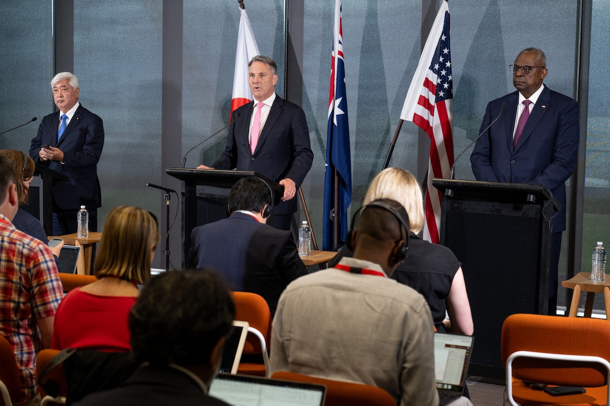 Three men speak to reporters during a press conference.