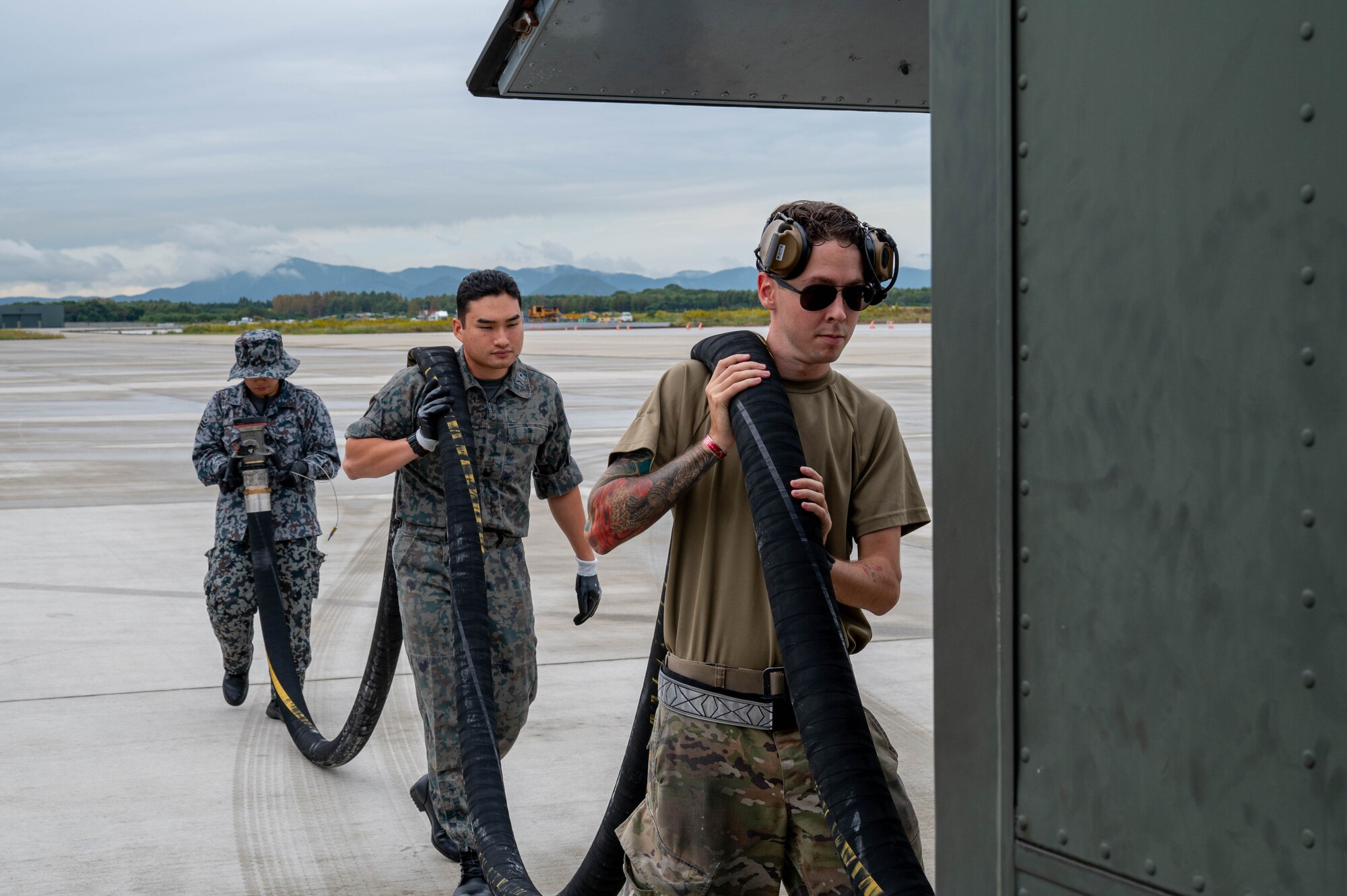 U.S. Air Force Senior Airman Dakota Adams-Petree, 77th Expeditionary Fighter Generation Squadron aircraft fuel systems journeyman, and members of the Japan Air Self-Defense Force stow a fuel hose during Keen Sword 25 at Tsuiki Air Base, Japan, Oct. 28, 2024.