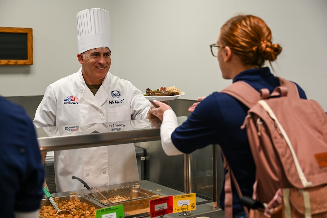 Col. Douglas A. Perry Jr., 445th Airlift Wing commander, hands 445th Development and Training Flight trainee Taylor Susil her lunch at the Pitsenbarger Dining Facility, Wright-Patterson Air Force Base, Ohio Nov. 3, 2024. Commanders, first sergeants and chiefs served Airmen at the dining facility to show their appreciation for their service. (U.S. Air Force photo/Master Sgt. Patrick O’Reilly)