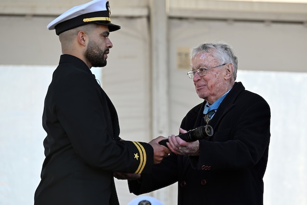 Medal of Honor recipient Thomas Kelley, a retired Navy captain, presents the long glass to the officer of the deck Lt. Steven Lewis during the commissioning ceremony for USS Nantucket in Boston.