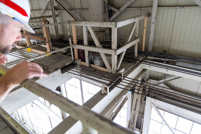 A man in a white hardhat looks at grey metal beams.