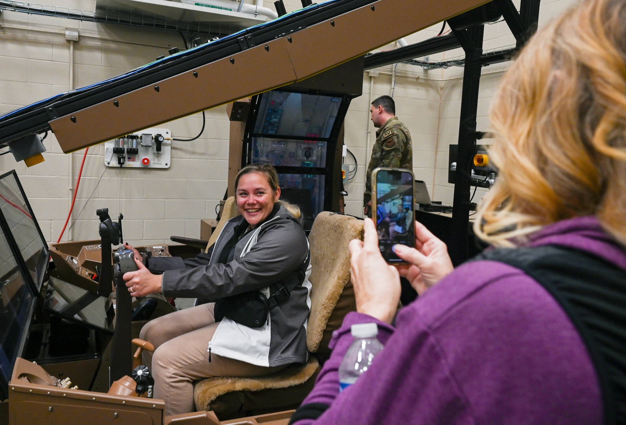 Dana Houser, right, Douglas High School counselor, takes a picture of Bailey Echer, Andover Central High School counselor, sitting inside a KC-46A Pegasus maintenance simulator during a base tour Nov. 6, 2024, at McConnell Air Force Base, Kansas. The purpose of the tour was to offer deeper insight into life in the military for local guidance counselors and military liaisons, as well as provide an opportunity for them to develop working relationships with active duty, Guard and Reserve recruiters. (U.S. Air Force photo by Staff Sgt. Tryphena Mayhugh)