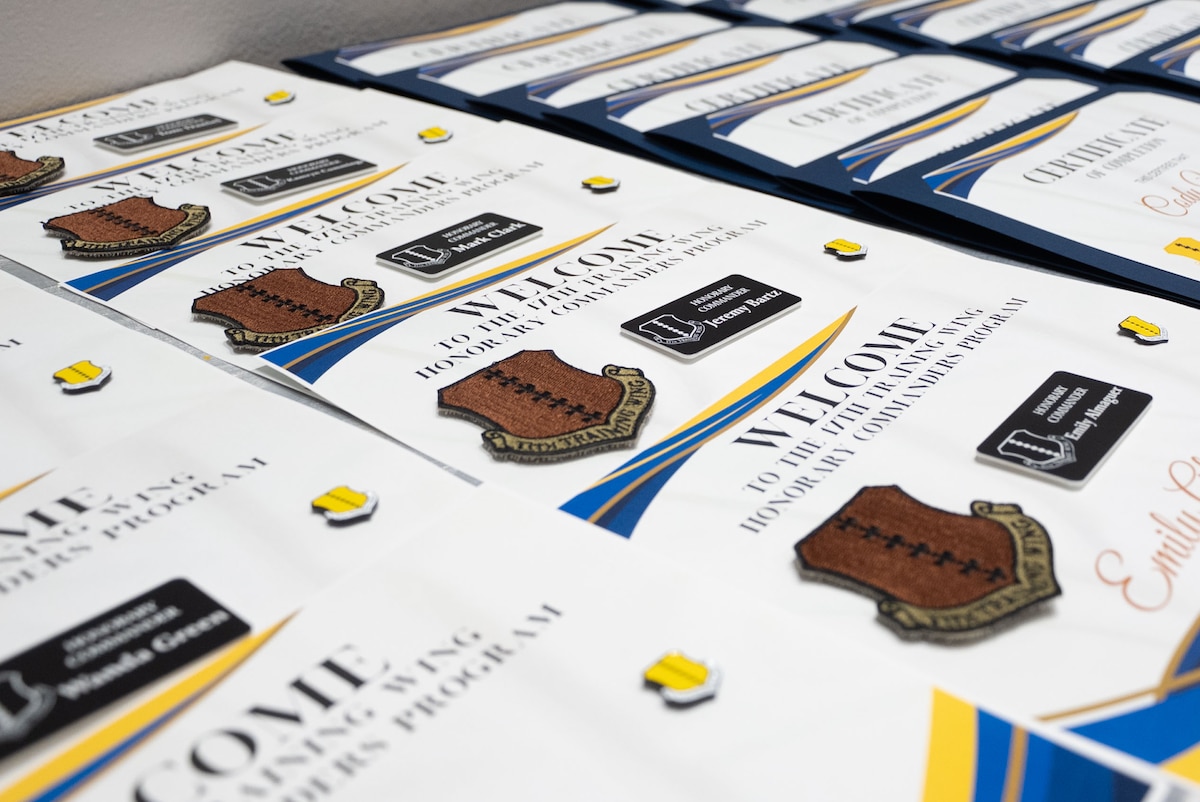 Graduation certificates and induction welcome packages on an awards table during the 2024 Honorary Commander Graduation and Induction ceremony at the Powell Event Center, Goodfellow Air Force Base, Texas, Nov. 7, 2024. Certificates are awarded to Honorary Commanders who participate and graduate from the year-long course. (U.S. Air Force photo by Airman 1st Class Brian Lummus)