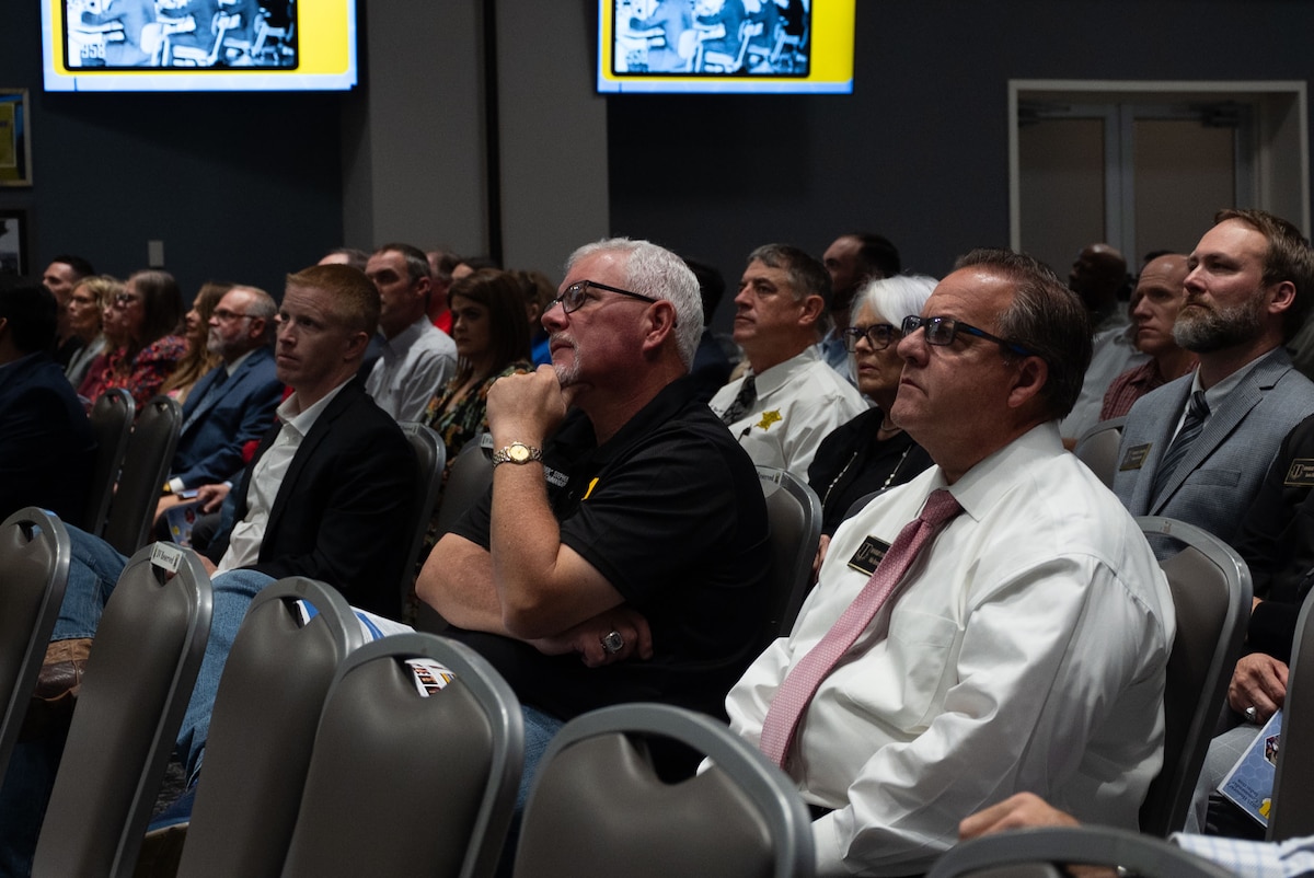 2024 Honorary Commander Graduation and Induction ceremony attendees watch the Goodfellow mission brief video during the ceremony at the Powell Event Center, Goodfellow Air Force Base, Texas, Nov. 7, 2024. The mission brief video is played so all viewers understand Goodfellow’s role and history within the Air Force and joint training environment. (U.S. Air Force photo by Airman 1st Class Brian Lummus)