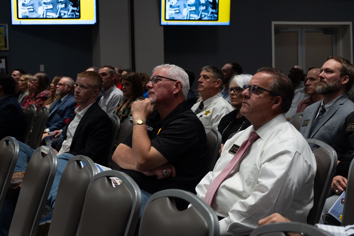 2024 Honorary Commander Graduation and Induction ceremony attendees watch the Goodfellow mission brief video during the ceremony at the Powell Event Center, Goodfellow Air Force Base, Texas, Nov. 7, 2024. The mission brief video is played so all viewers understand Goodfellow’s role and history within the Air Force and joint training environment. (U.S. Air Force photo by Airman 1st Class Brian Lummus)