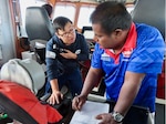 Ensign Go speaking to a member of the Kiribati Police Maritime Unit. The PMU member is writing on paper and looking at Ensign Go.