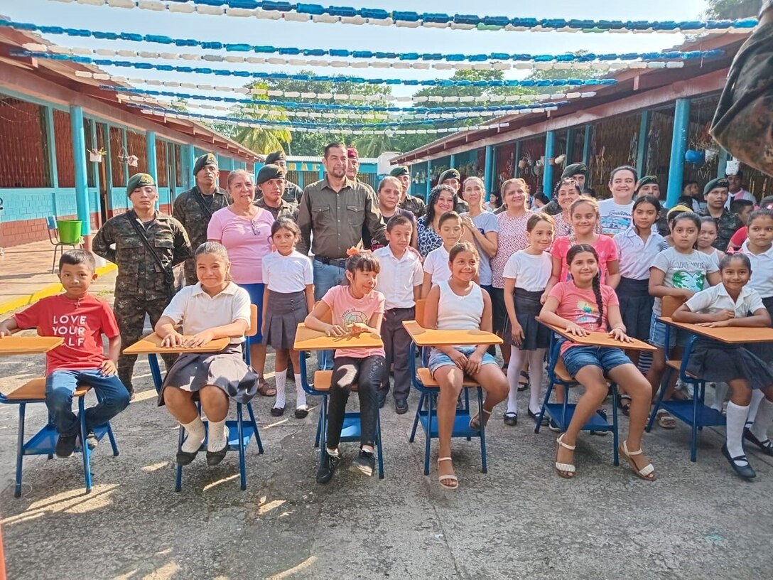 Students and school faculty from Puerto Barrios, Guatemala, pose alongside the Guatemalan military with desks donated through United States Agency for International Development and facilitated by the U.S. Army Civil Affairs team, Oct. 25, 2024. The U.S. military is committed to improving the lives of their partners throughout Central America by enhancing the quality of life for those residing in the region. (U.S. Army courtesy photo)