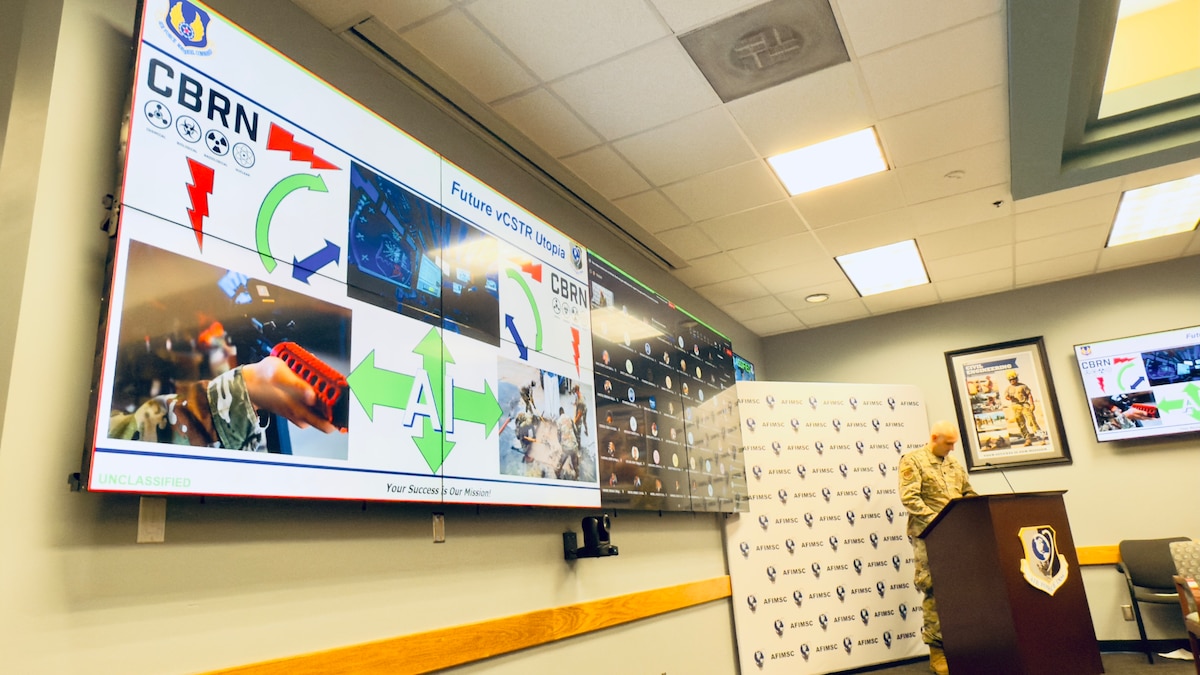 Airmen giving a briefing during AFIMSC IWEPTAC event to leadership in a conference room.