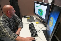 Ryan Laughery sits at desk using a computer to run computational fluid dynamics software.