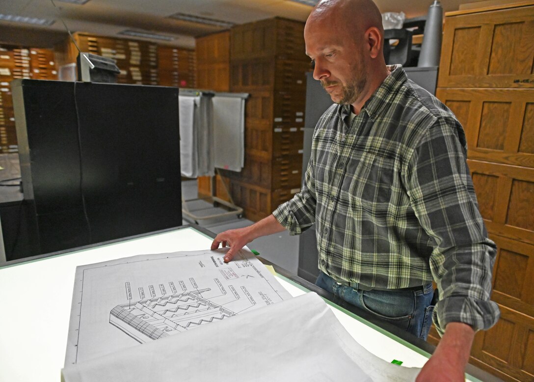Ryan Laugherym an engineer, examines paper blueprints in a archive.
